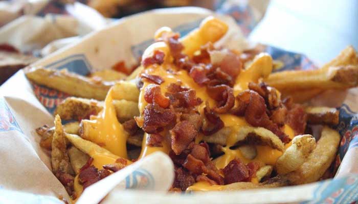 Fresh cut French fries topped with cheese and bacon from appetizer menu at South Philly Cheese Steaks